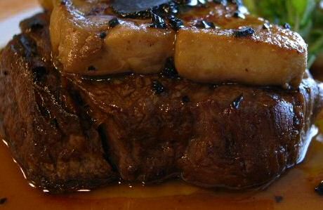 Een gebakken steak met rossinisaus en een stuk foie gras erbovenop geserveerd